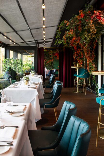 Luxury terrace dining setup with teal chairs and foliage at Chapter One Kent.