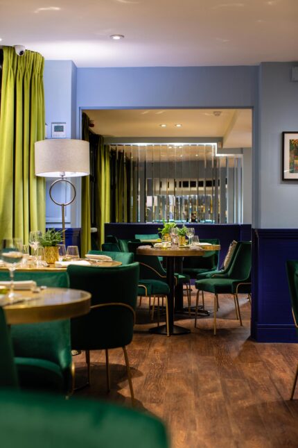 Intimate restaurant seating area with modern decor, green chairs, and wine glasses set for a memorial gathering.